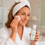 Woman applying skin toner with cotton pad