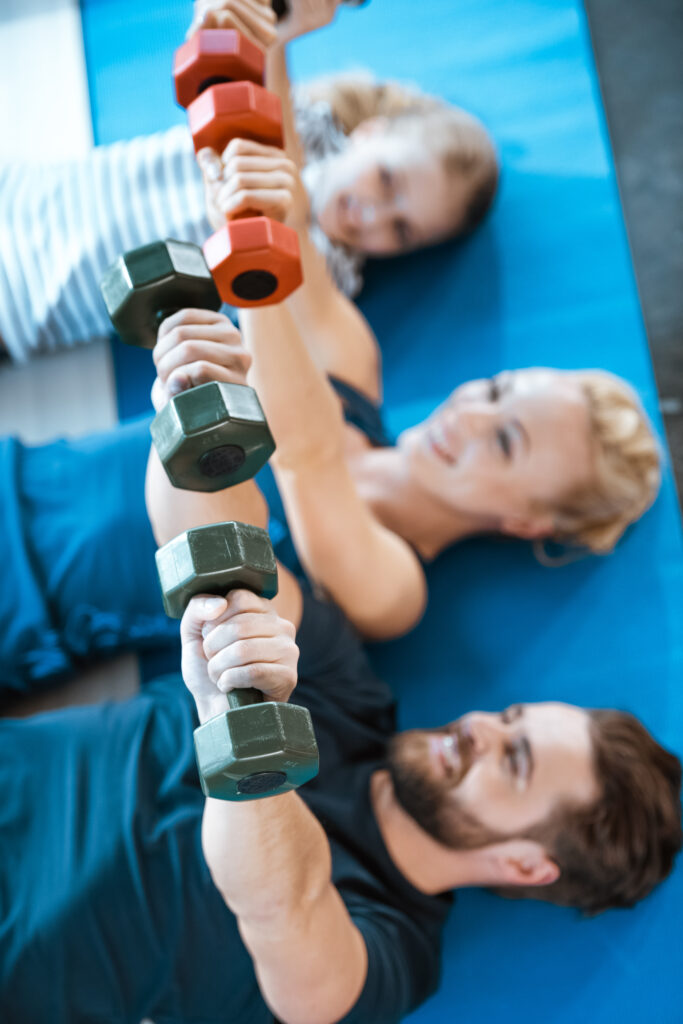 happy family exercising with dumbbells at fitness studio