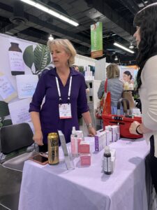 Woman at skincare booth with products displayed.