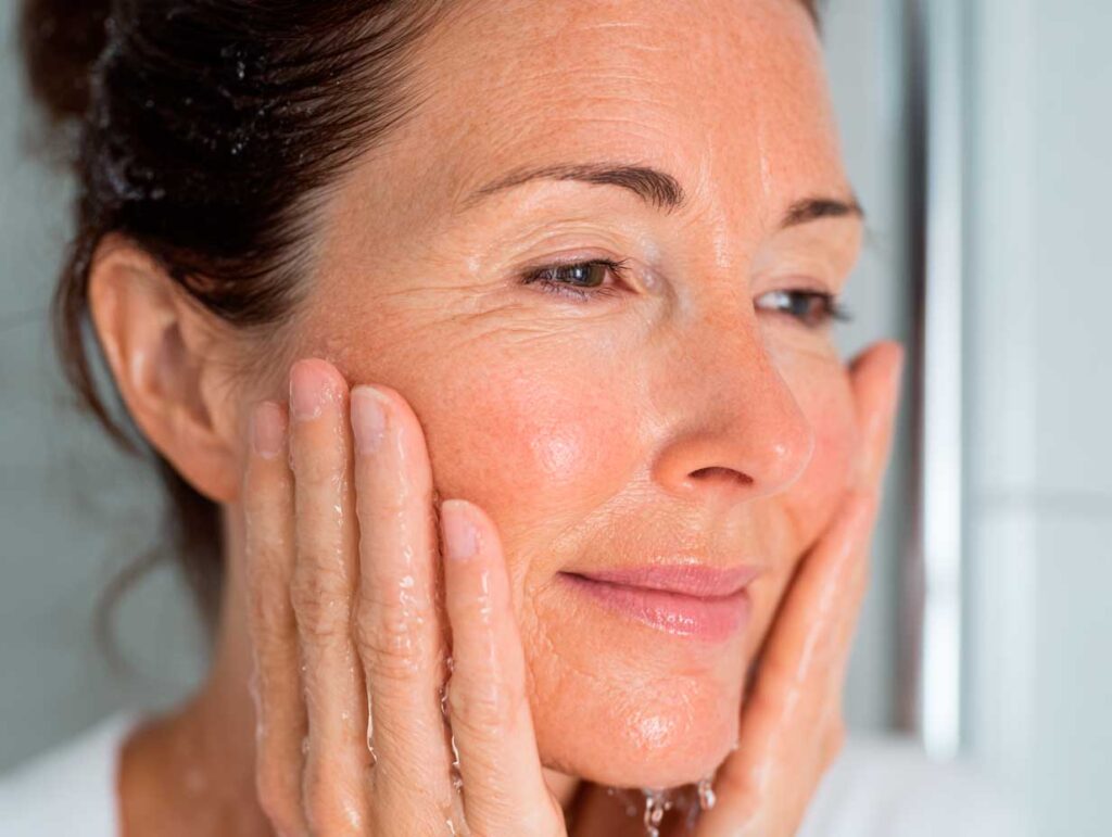 Woman washing face with water