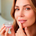 Woman applying lip repair mask for moisturizing lips.