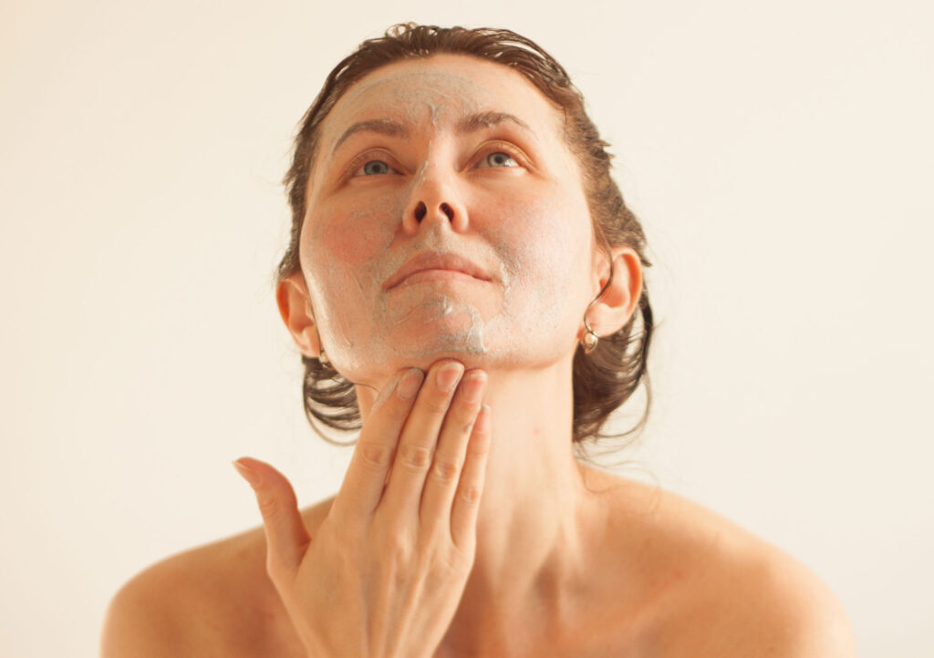 Woman applying face mask skincare treatment