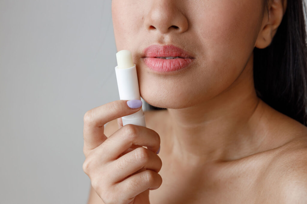 Woman applying lip balm to lips.