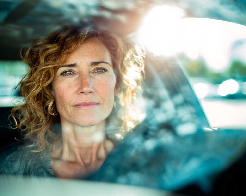 Woman sitting in car with sunlight streaming