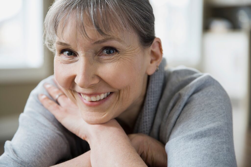 Smiling middle-aged woman resting chin on hands