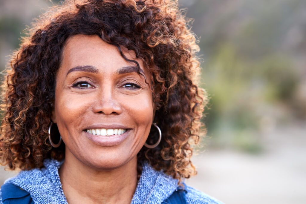 Smiling woman with curly hair outdoors portrait