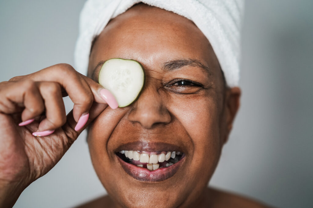 Smiling woman with cucumber slice over eye