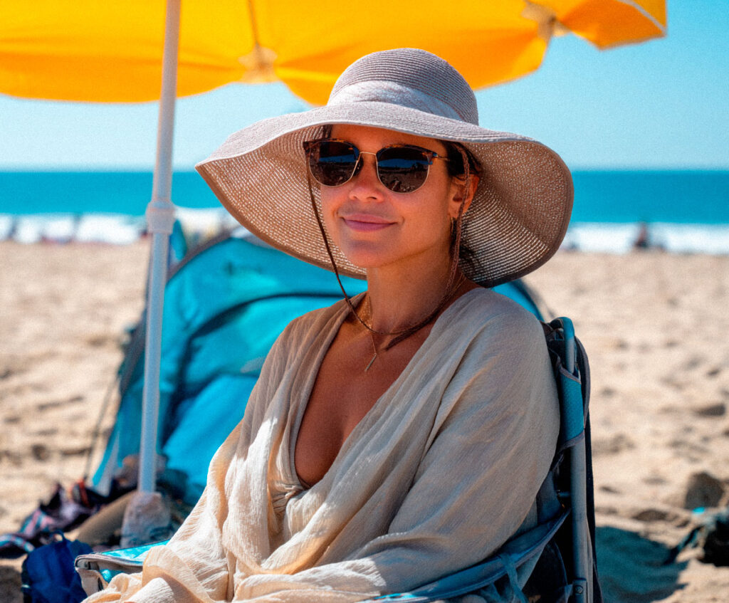 Woman relaxing under umbrella at sunny beach