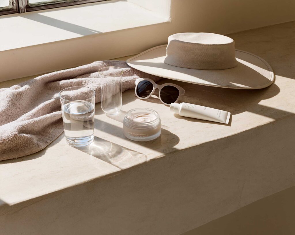 Sunlit skincare products with hat and sunglasses