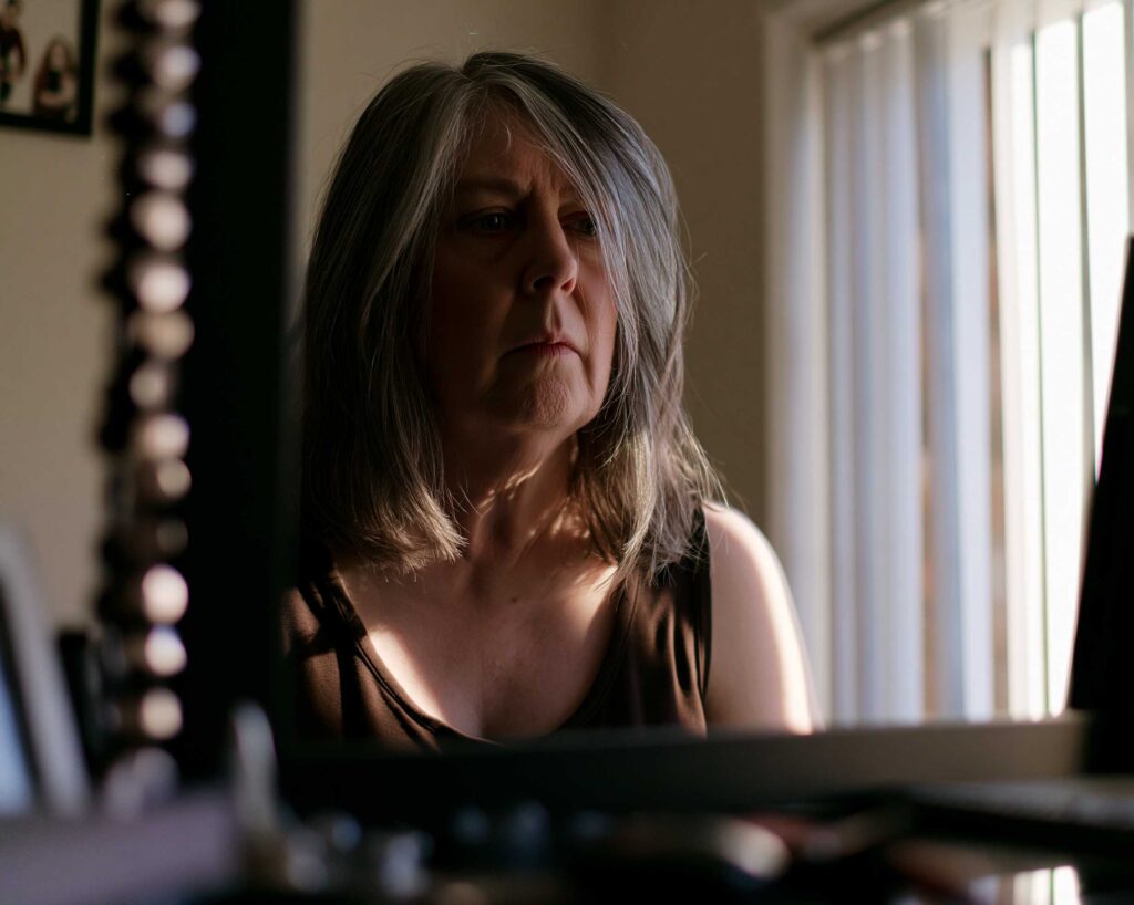 Older woman gazing thoughtfully by sunlit window