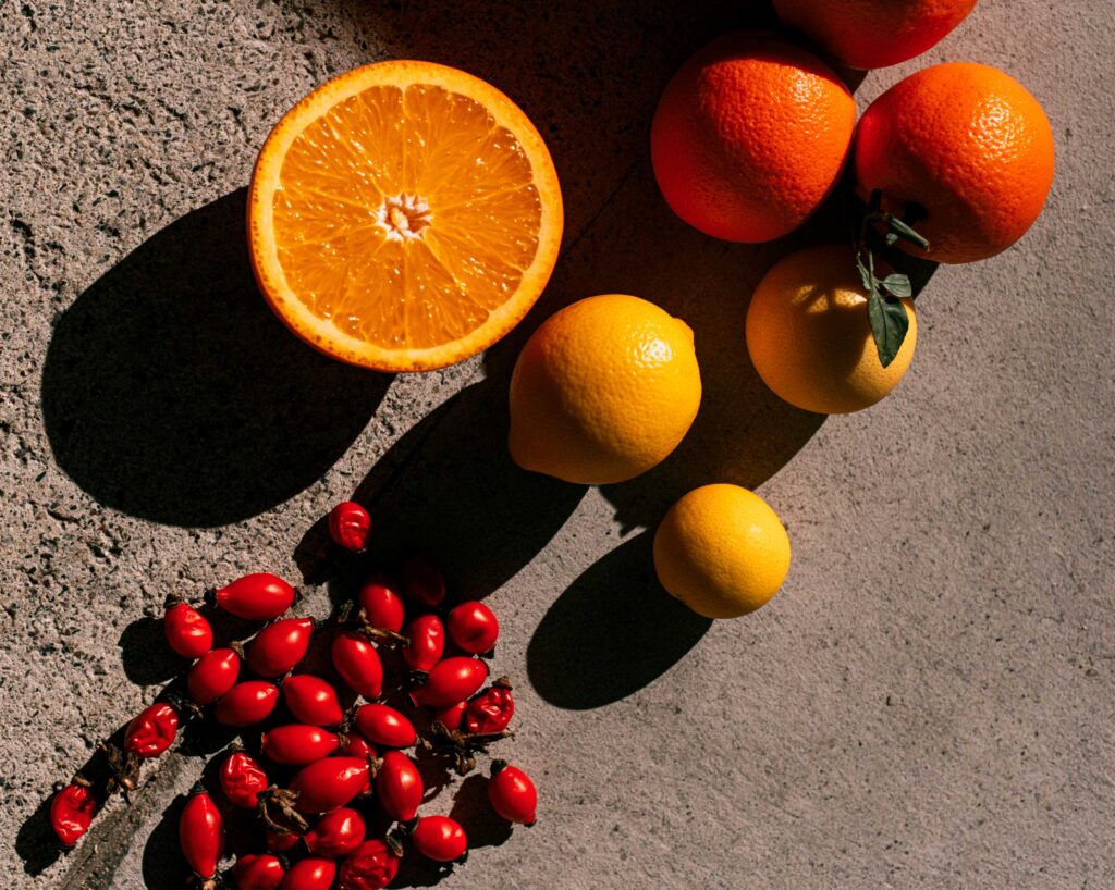 Halved orange, lemons, and red berries on concrete