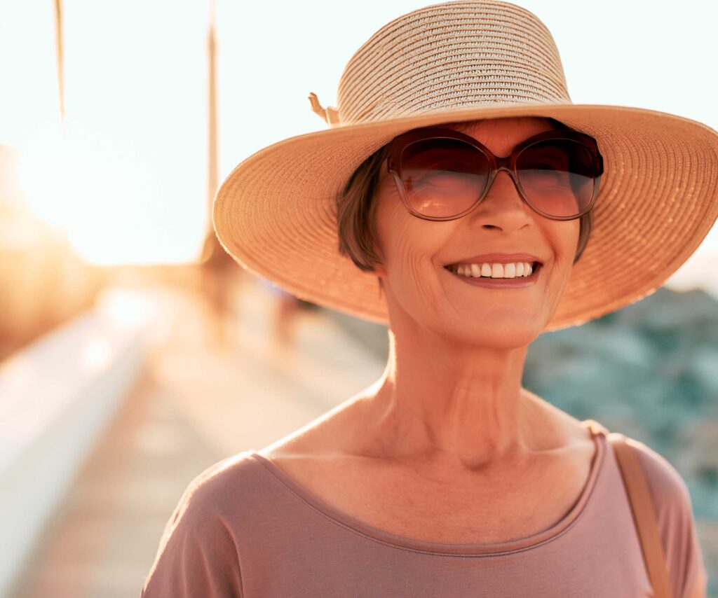 Smiling woman in sunhat and sunglasses at sunset