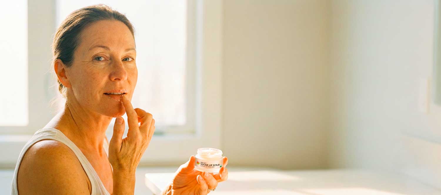 Woman applying lip scrub from small jar