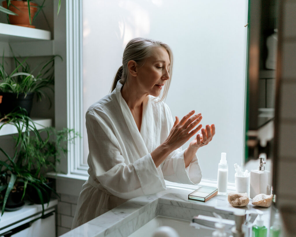 Woman applying skincare in bright bathroom