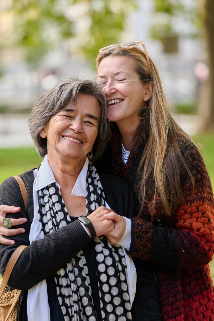 Two women smiling and hugging outdoors