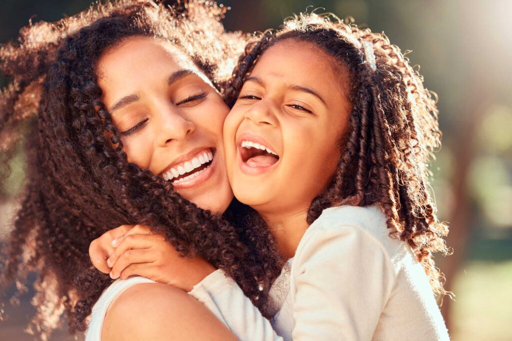 Mother and daughter hugging and laughing outdoors