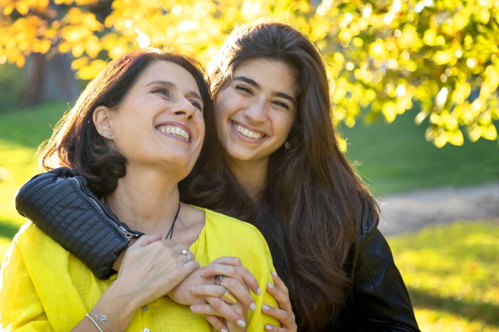 Mother and daughter smiling in sunny park
