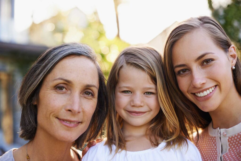 Three generations of women smiling outdoors