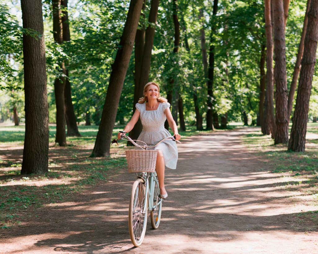 Woman riding bicycle on tree-lined park path