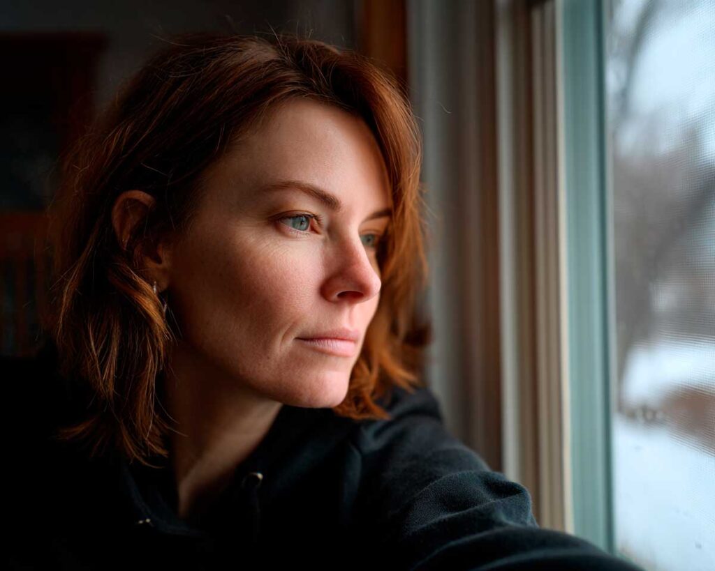 Woman gazing thoughtfully out a window indoors
