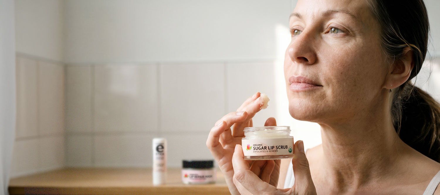 Woman applying organic sugar lip scrub in bathroom