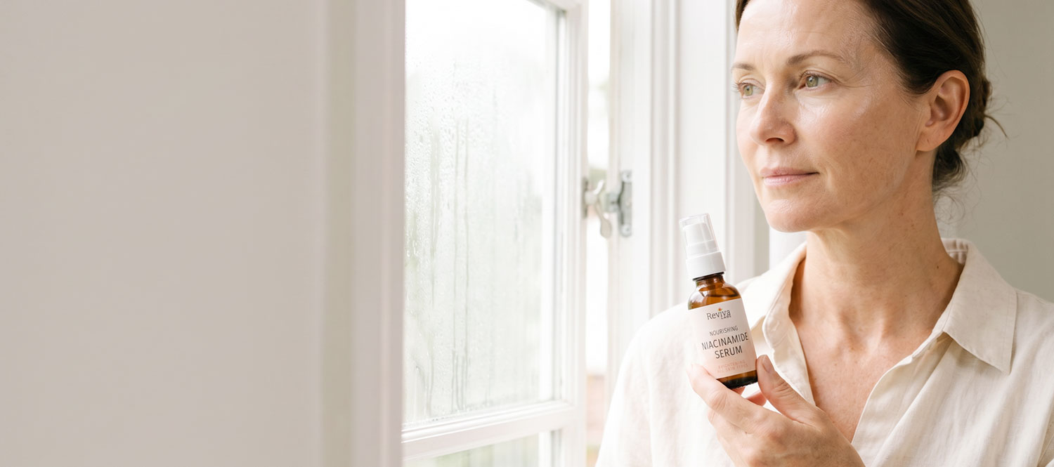 Woman holding niacinamide serum by window