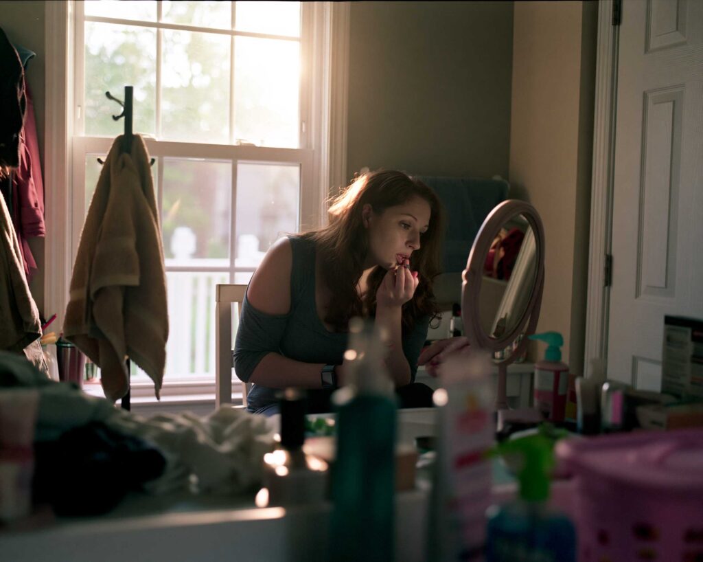 Woman applying lipstick at vanity mirror