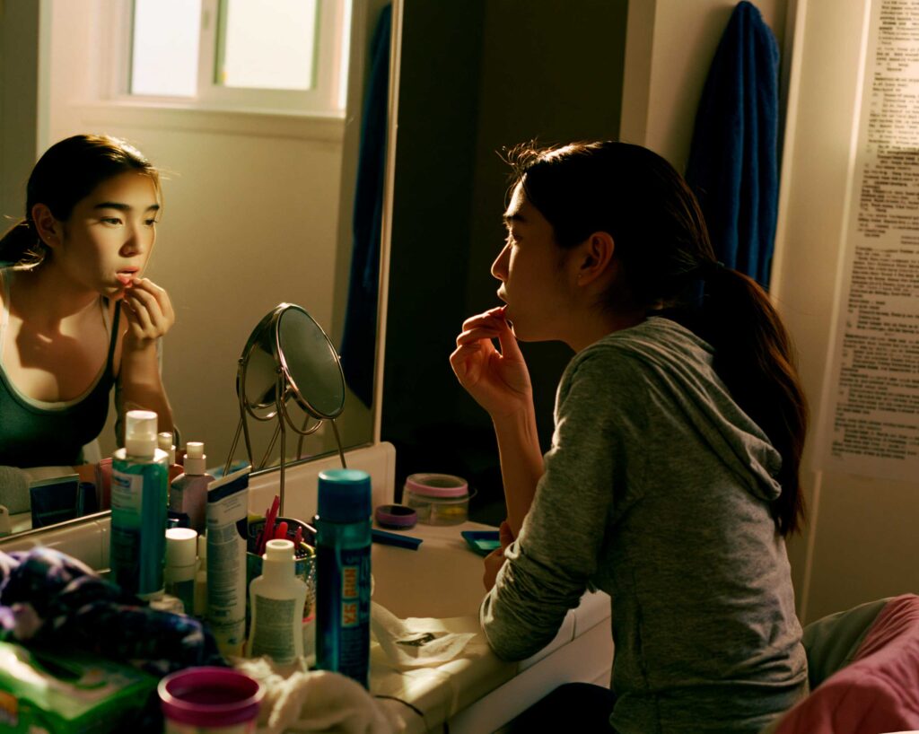 Woman applying lip balm at bathroom mirror