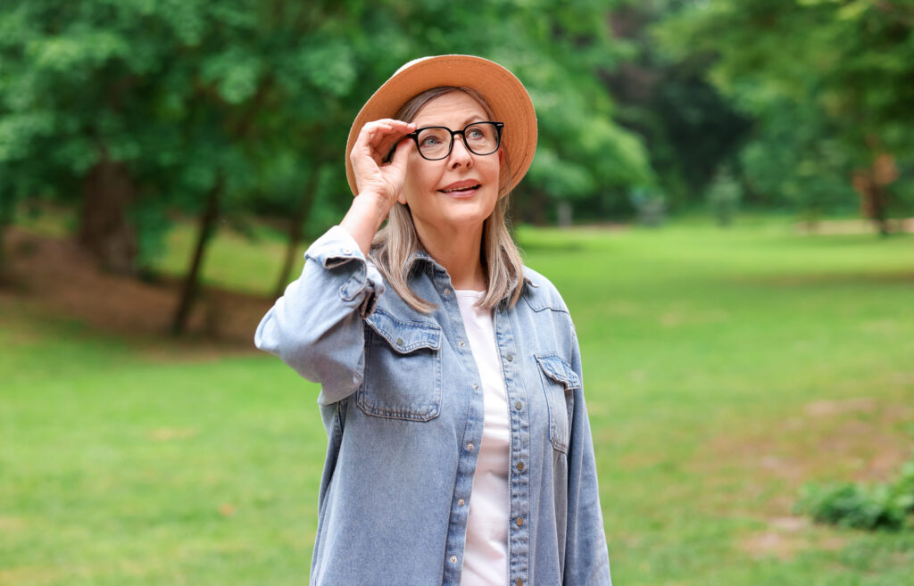 Woman adjusting glasses in sunny park
