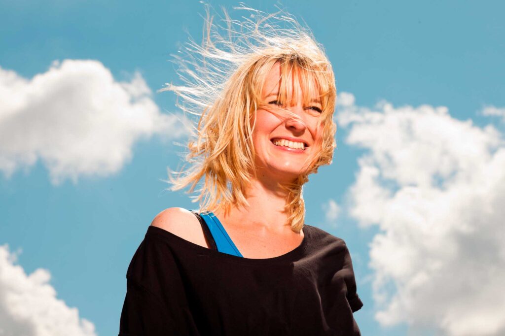 Smiling woman with windblown hair under blue sky