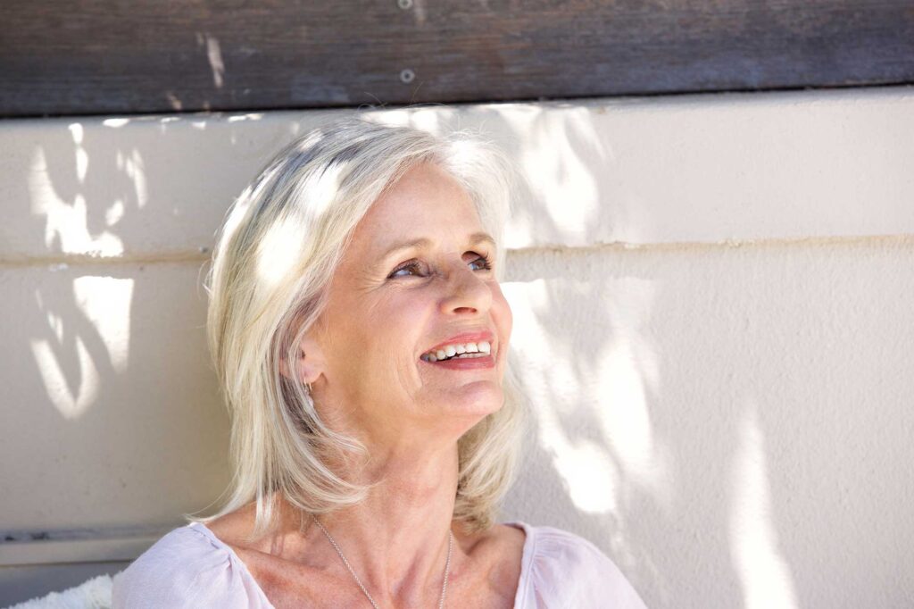 Smiling older woman looking upward in sunlight