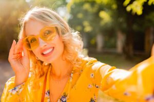Smiling woman in yellow sunglasses taking selfie
