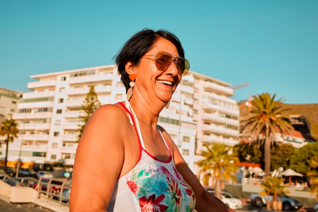 Smiling woman in sunglasses at sunny beachside city
