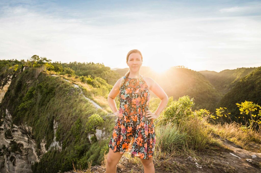 Woman standing on cliff at sunset