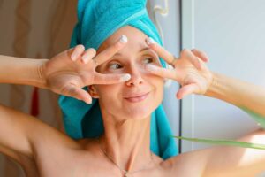 Woman applying facial cream with towel wrapped hair