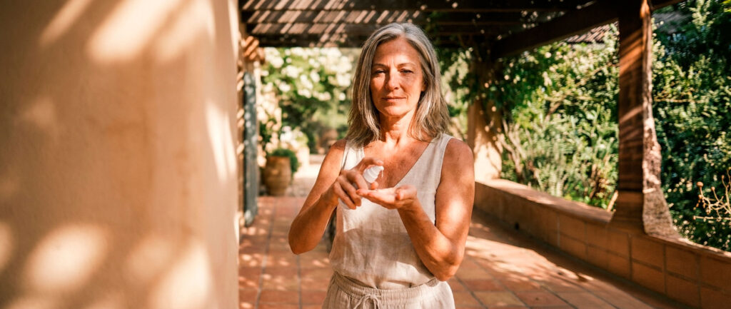 Woman applying lotion on sunlit patio
