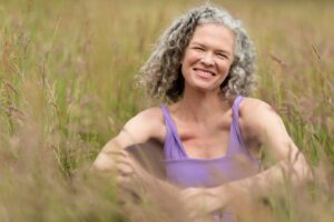 Smiling woman with gray hair in grassy field