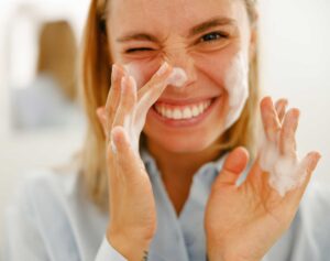 Woman applying foamy facial cleanser to her face