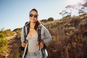 Woman hiking on sunny trail with backpack
