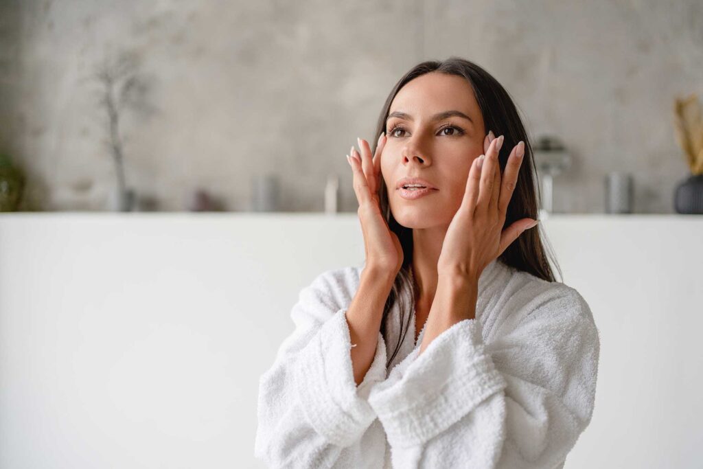 Woman applying skincare in bathroom mirror