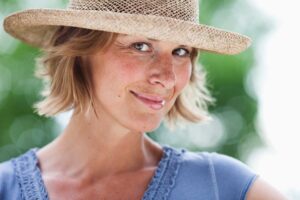 Woman in straw hat smiling outdoors