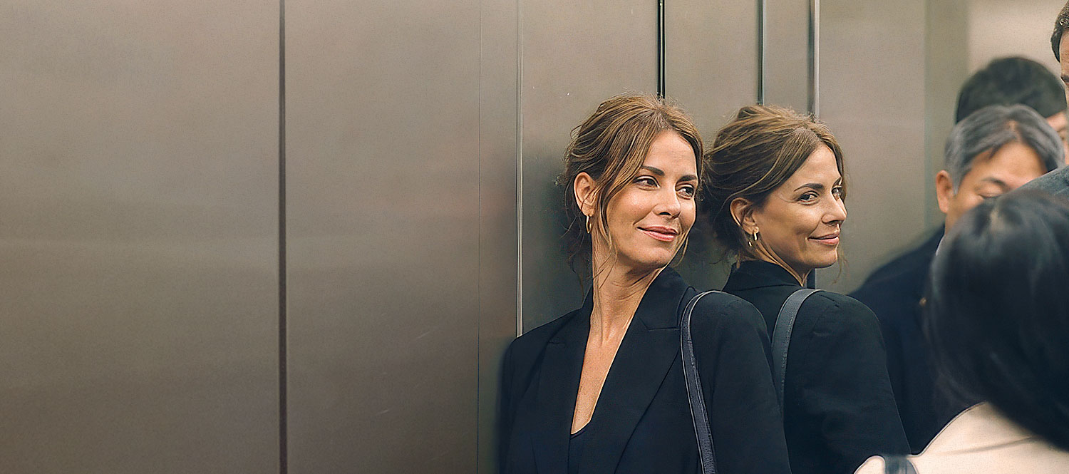 Woman smiling at reflection in elevator mirror