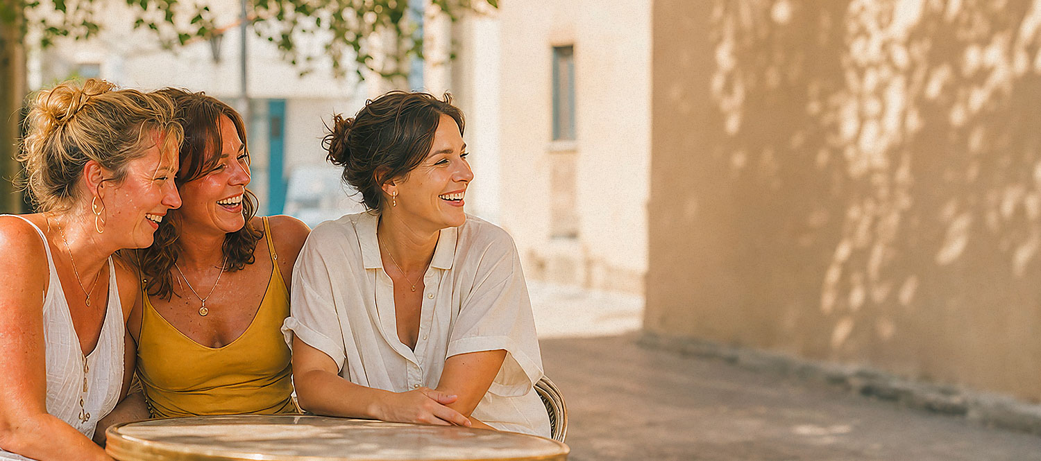 Three women laughing at outdoor café table