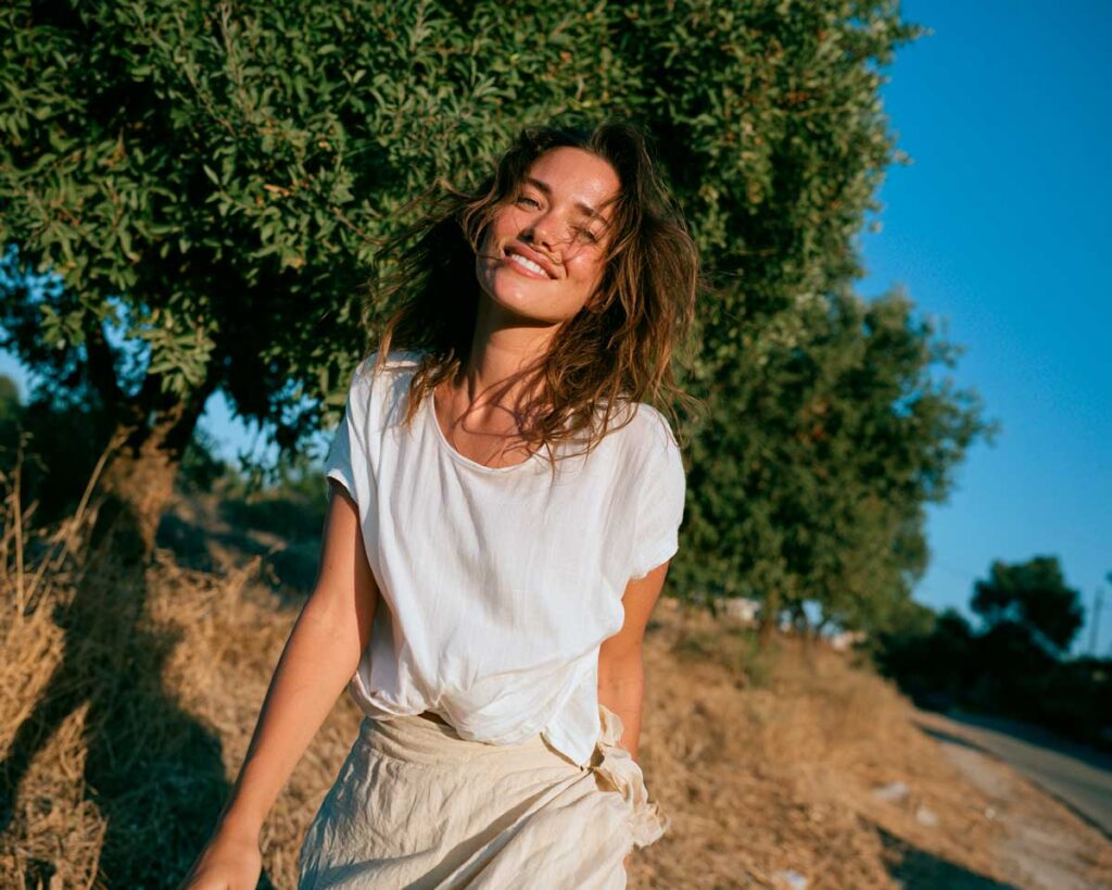 Smiling woman walking outdoors in sunny countryside