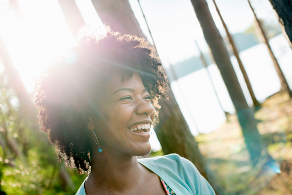 Smiling woman in sunlight among trees