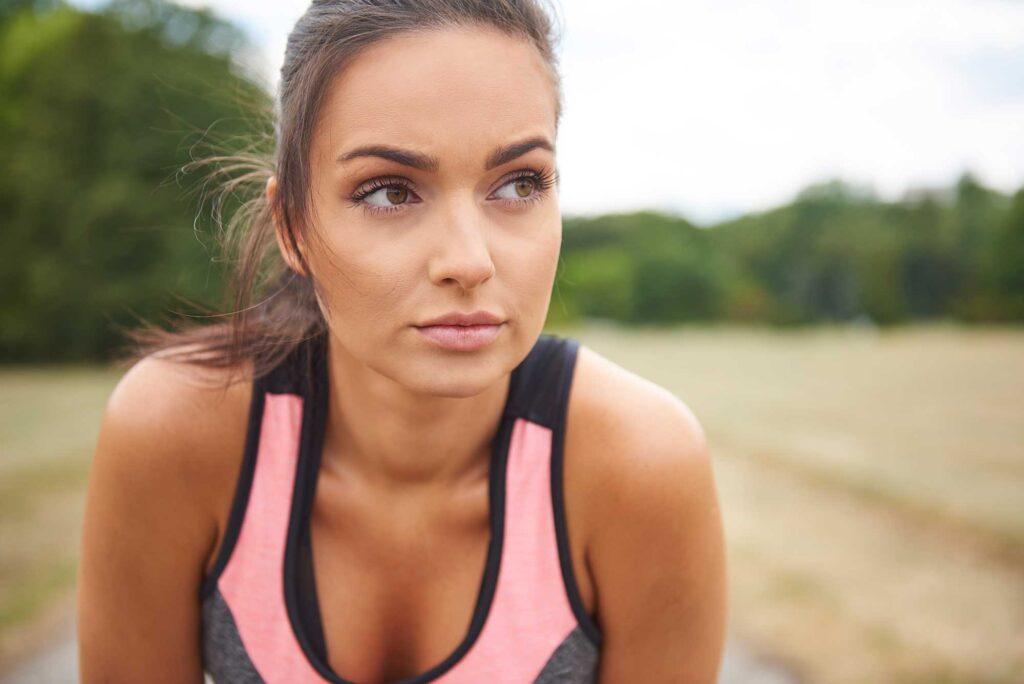 Focused woman resting outdoors after workout
