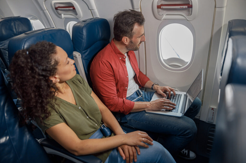 passengers on an airplane one working on laptop 2026 03 10 01 09 43 utc
