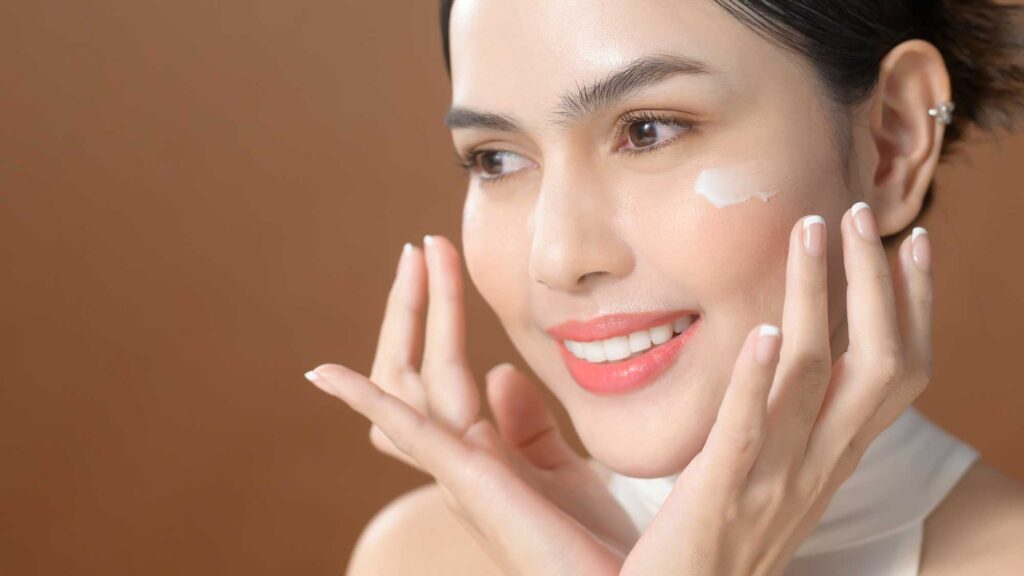 Woman applying facial moisturizer to her cheek