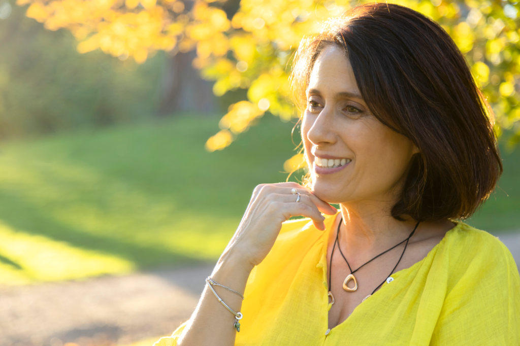 Smiling woman in yellow blouse outdoors at sunset