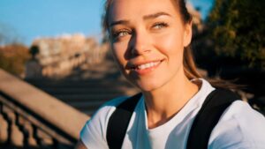 Smiling woman outdoors at sunset with backpack